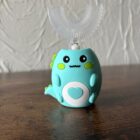 Na obrazku widać jak szczoteczka elektryczna w kolorze turkusowym jest postawiona na biurku.